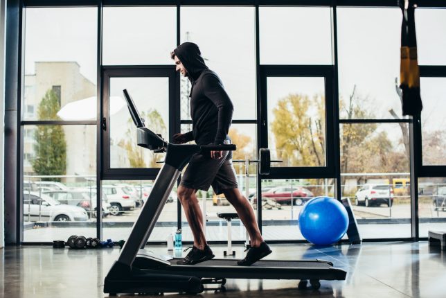 Man Wearing Hoodie Running on Treadmill